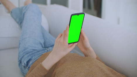 Young-Girl-Is-Holding-Smartphone-With-Green-Screen-At-Evening-Time.-Smartphone-in-hand-static-footage-with-little-hand-moves.-indicators-on-screen-to-track-movement